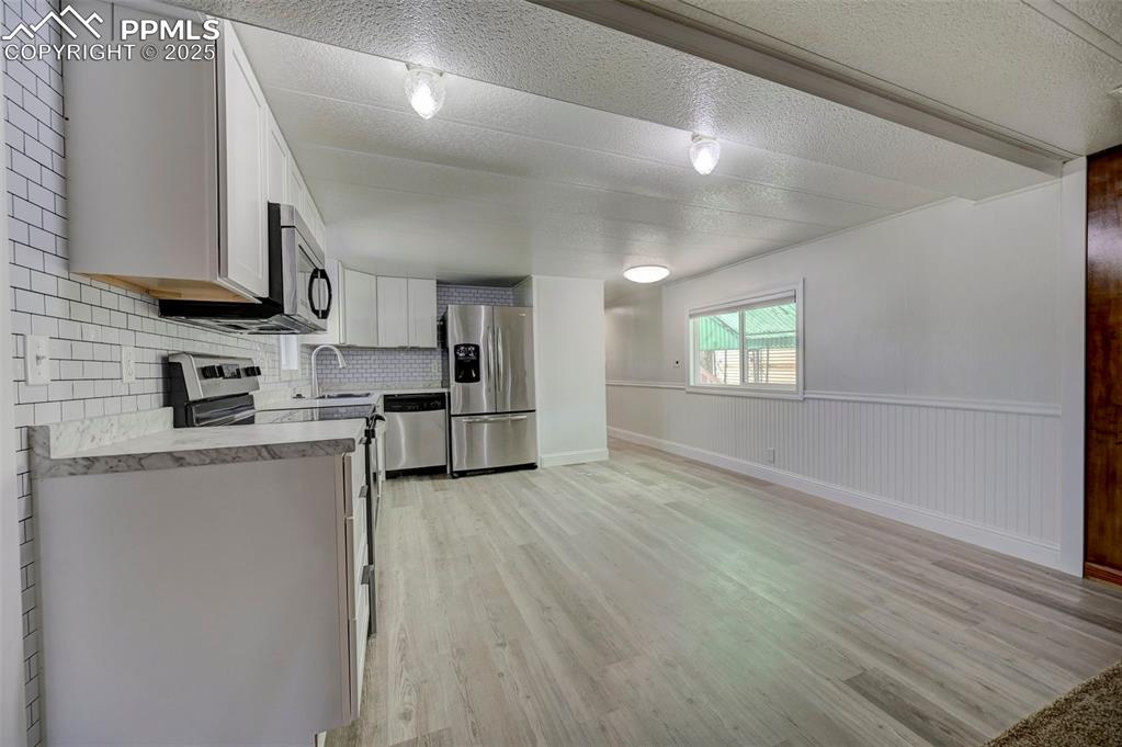 Image 8 of 26: Kitchen with stainless steel appliances, light wood-type flooring, light co