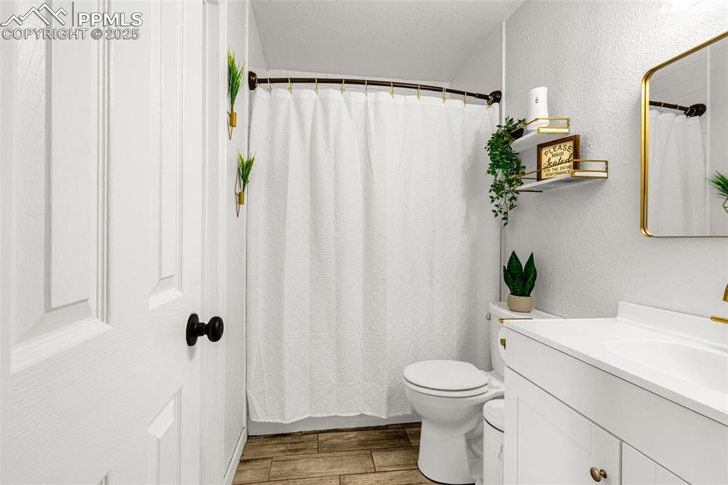 Image 13 of 34: Bathroom with vanity, wood finished floors, and curtained shower