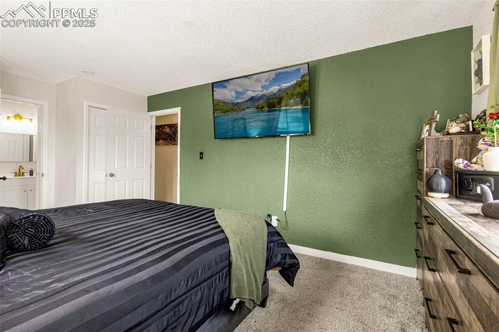 Image 16 of 34: Carpeted bedroom with a textured wall, a textured ceiling, and a closet