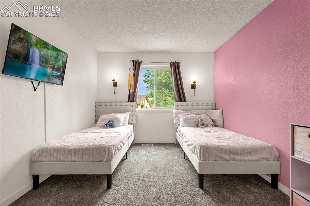 Image 18 of 34: Carpeted bedroom with a textured ceiling and a textured wall