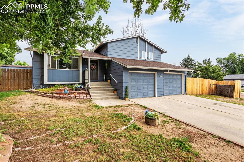 Image 2 of 34: Split level home with concrete driveway, an attached garage, and a shingled