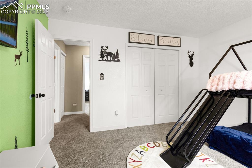 Image 21 of 34: Carpeted bedroom with a textured ceiling and a closet