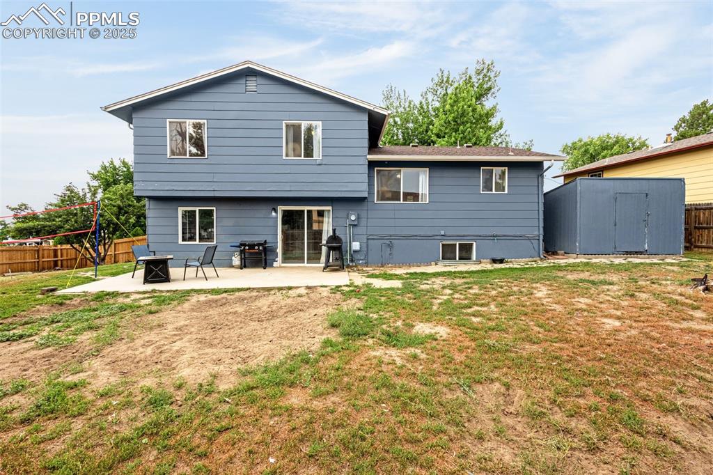 Image 26 of 34: Back of house with a patio, a storage shed, a fenced backyard, and a fire p