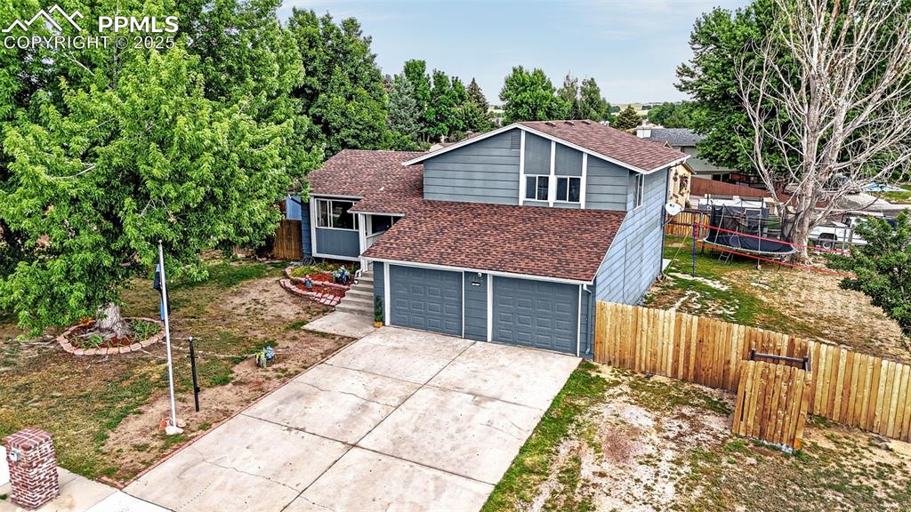 Image 29 of 34: View of front facade with a trampoline, a shingled roof, concrete driveway,