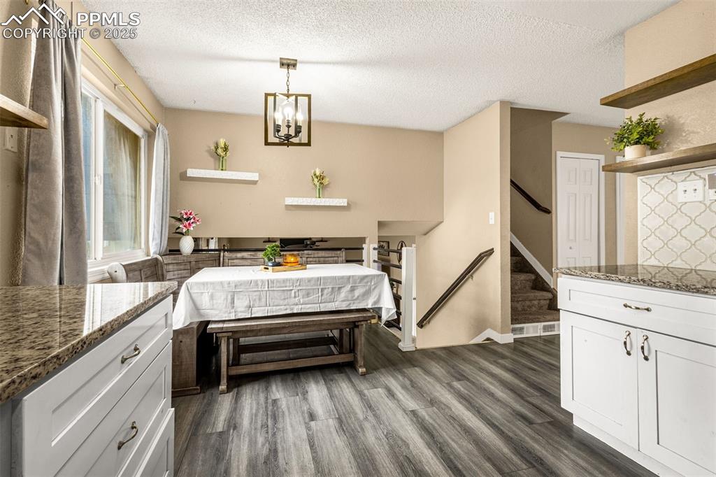 Image 8 of 34: Dining area with dark wood-style floors, a textured ceiling, stairway, and 