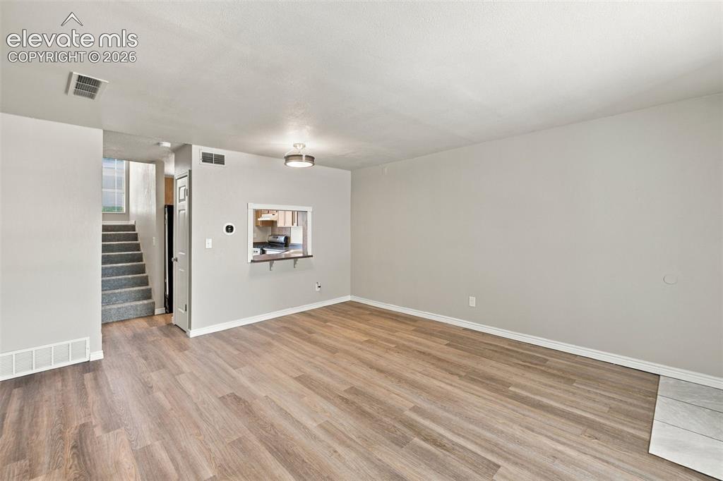 Image 12 of 26: Spacious open living area showcasing wood-finish flooring, neutral wall fin