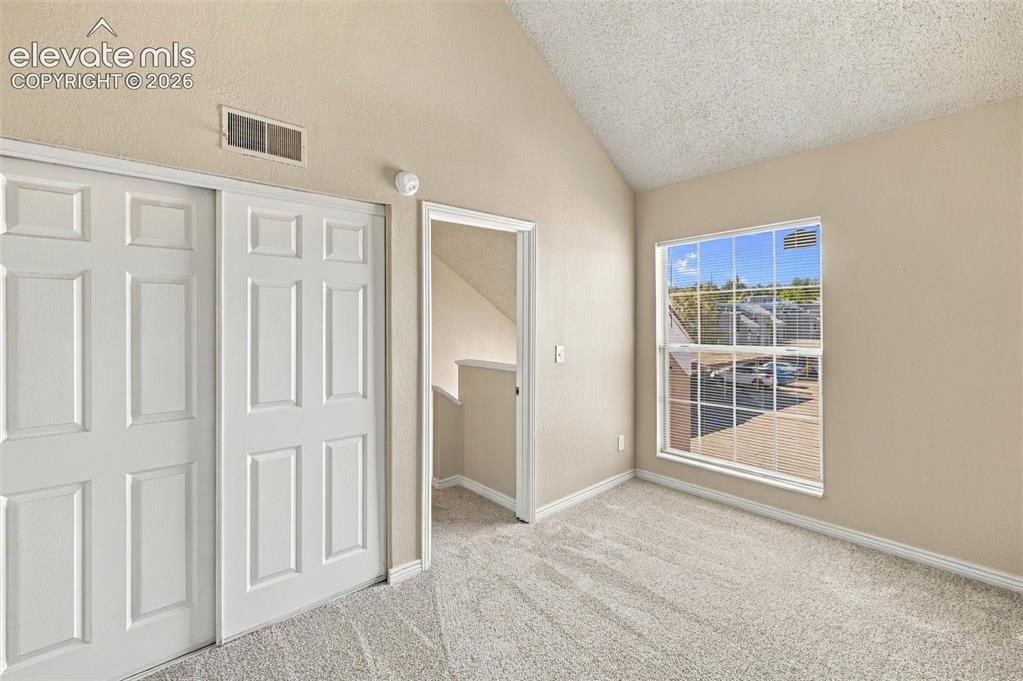 Image 13 of 26: Bright bedroom with expansive windows framing natural light, neutral carpet