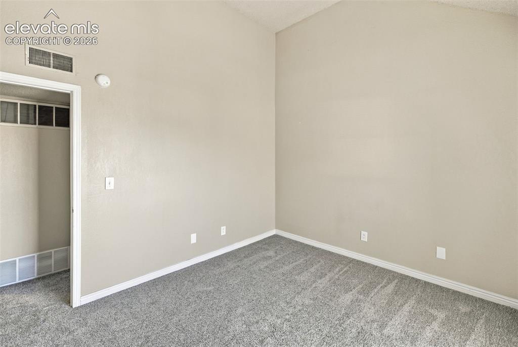 Image 16 of 26: Vaulted ceiling, light neutral wall paint, gray carpet flooring, and white 