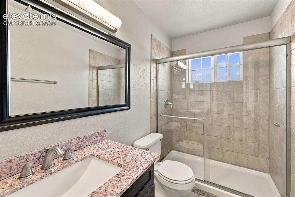 Image 17 of 26: Shower enclosure with glass sliding doors, tiled walls, and a window