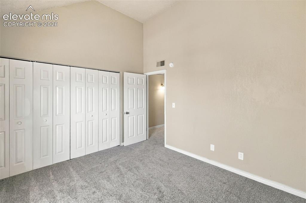 Image 19 of 26: Vaulted ceiling, neutral wall paint, light gray carpeting, bi-fold closet d