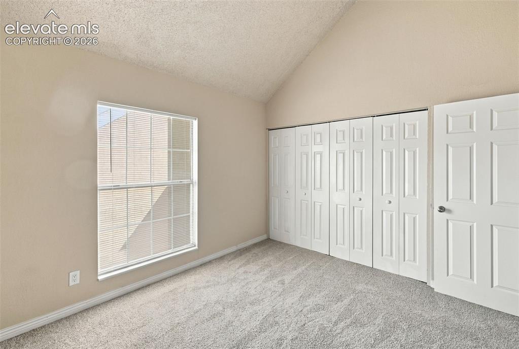 Image 20 of 26: Bright bedroom with large double-hung window, soft neutral walls, plush car