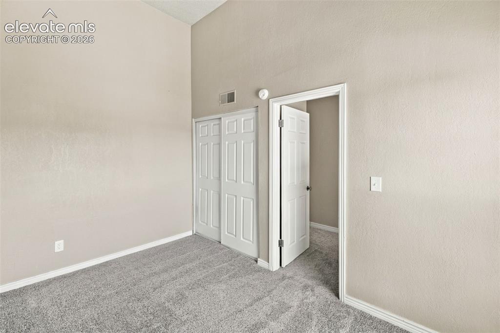 Image 21 of 26: Bright, neutral bedroom featuring neutral carpet flooring, white six-panel