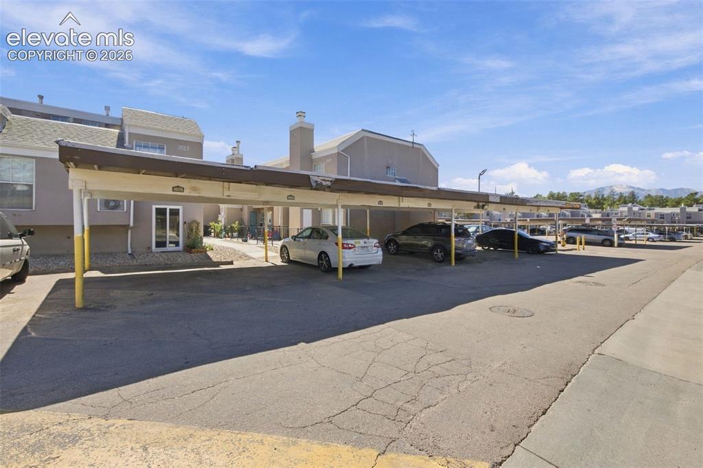 Image 26 of 26: Carport parking structure with a stucco-finish building exterior
