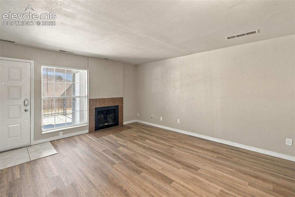 Image 3 of 26: Spacious living area showcasing wood-finish flooring throughout, a gas fire