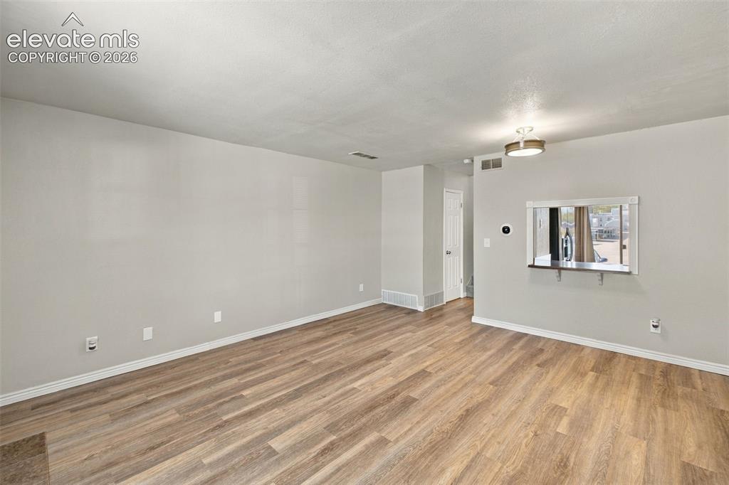 Image 5 of 26: Bright, open living space featuring warm wood-finish flooring throughout, n