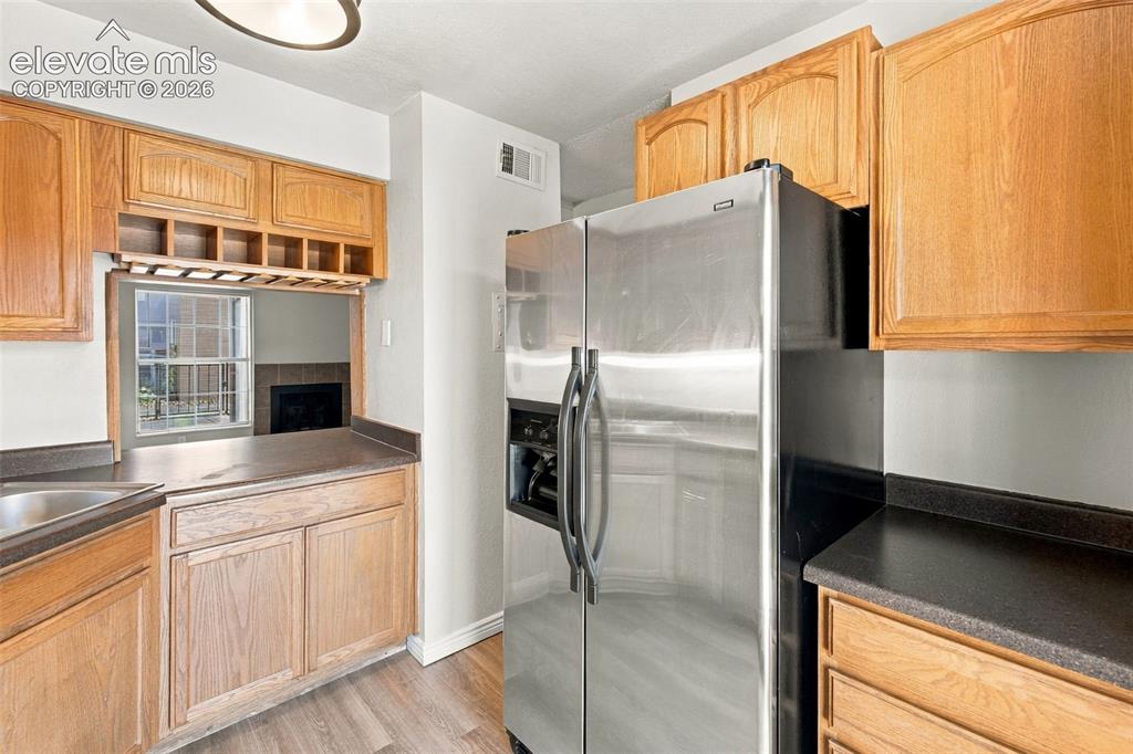 Image 7 of 26: Kitchen featuring wood-finish cabinetry, dark countertops, wood-finish floo