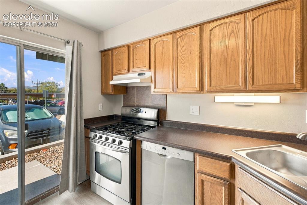 Image 8 of 26: Kitchen featuring wood cabinetry, stainless steel range, and a sliding glas
