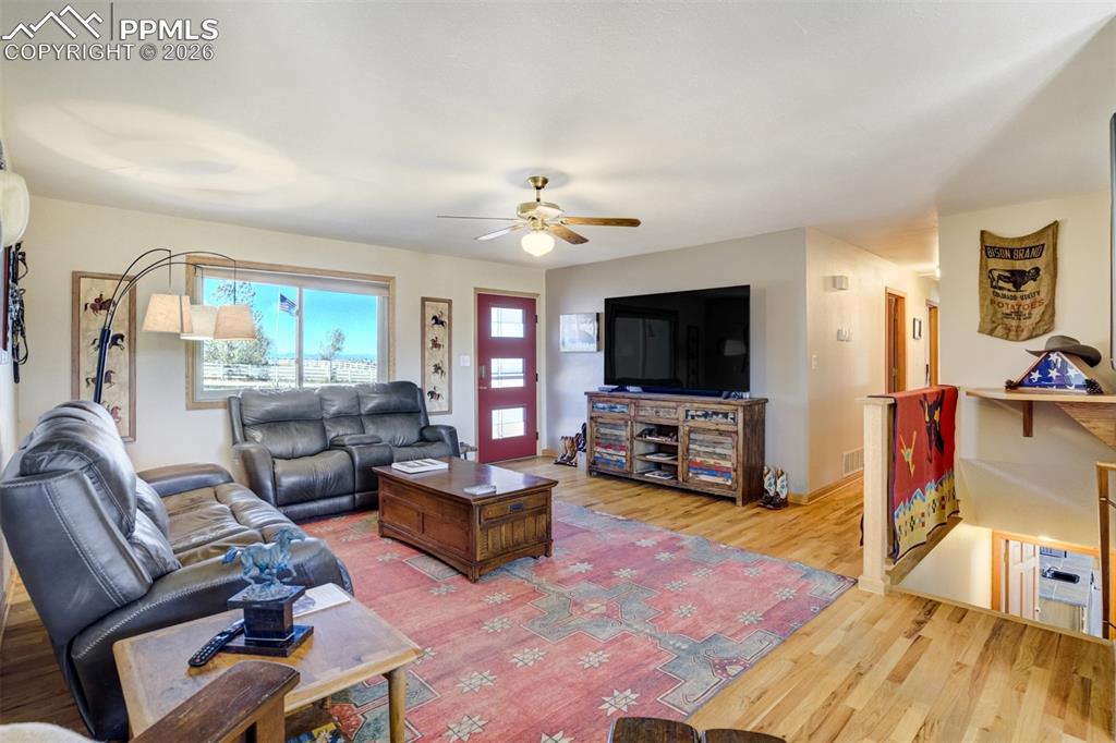 Image 13 of 50: Living area with light wood-style flooring and ceiling fan