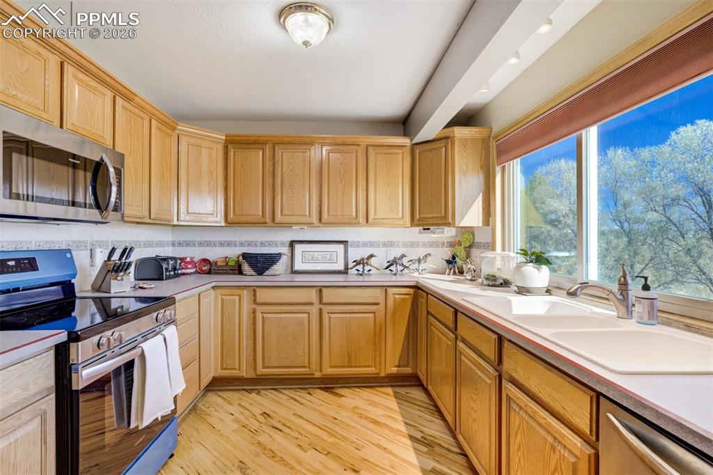 Image 16 of 50: Kitchen with stainless steel appliances, light wood-type flooring, and ligh