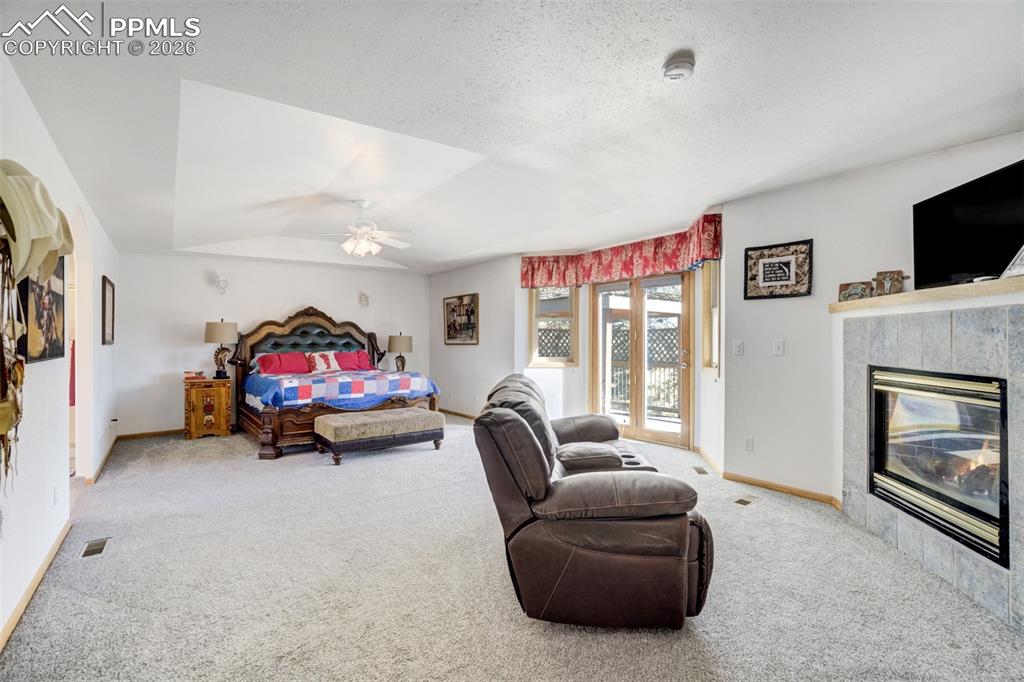 Image 19 of 50: Bedroom with access to exterior, light colored carpet, a tile fireplace, a