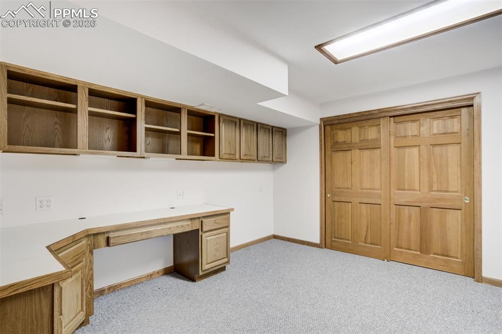 Image 39 of 50: Unfurnished office featuring built in desk and light colored carpet