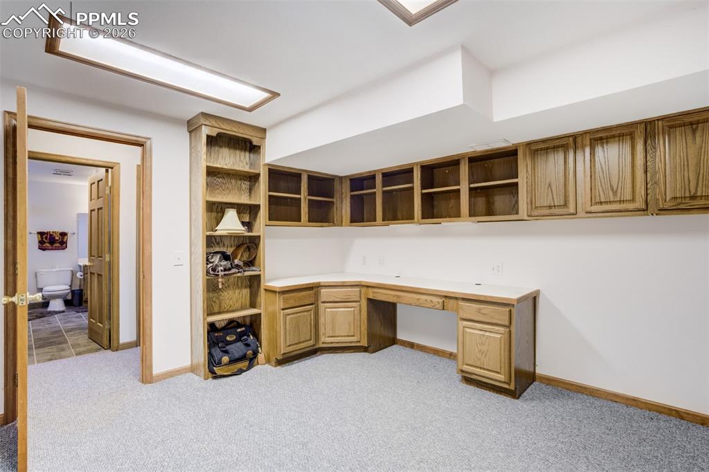 Image 40 of 50: Unfurnished office with built in desk and light carpet