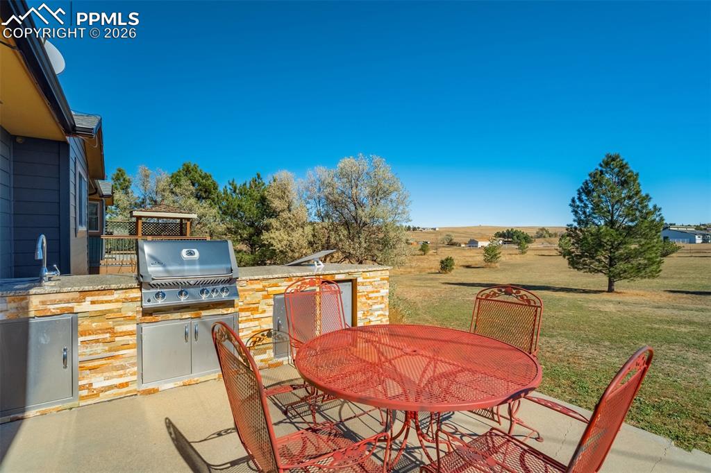 Image 42 of 50: View of patio featuring an outdoor kitchen / dining area and a rural view