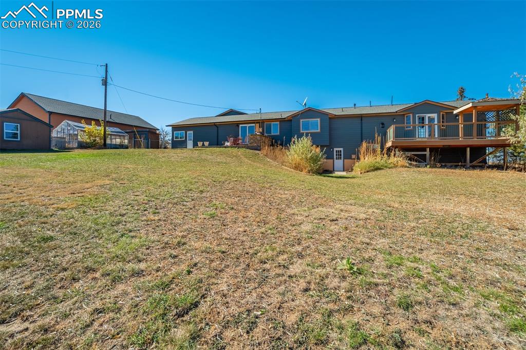Image 44 of 50: Rear view of house featuring a wooden deck and a yard