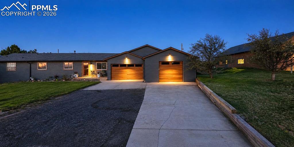 Image 50 of 50: Ranch-style exterior with gray siding, two-car garage featuring wood-finish
