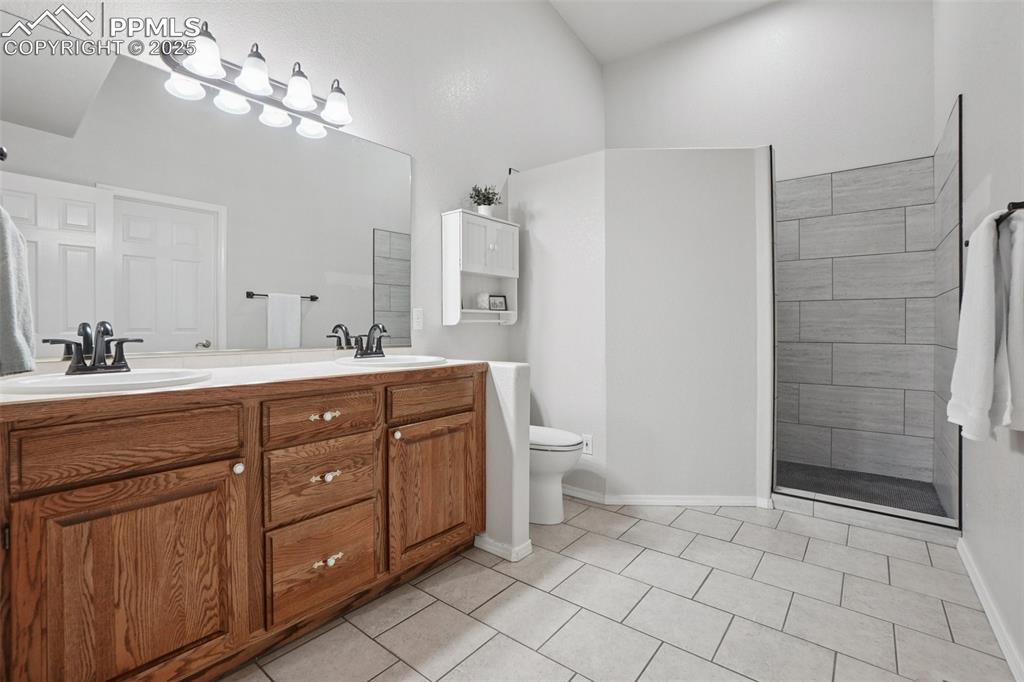 Image 23 of 42: Ensuite bathroom featuring double vanity, light tile patterned flooring, a