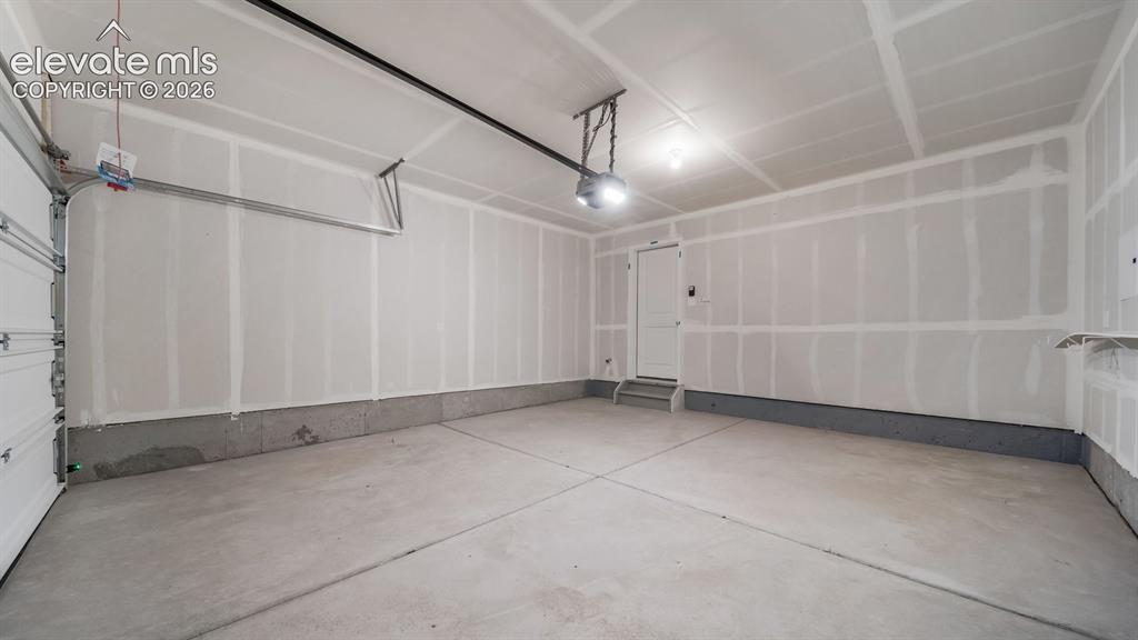 Image 10 of 24: Spacious garage featuring a concrete floor, overhead lighting, and an inter