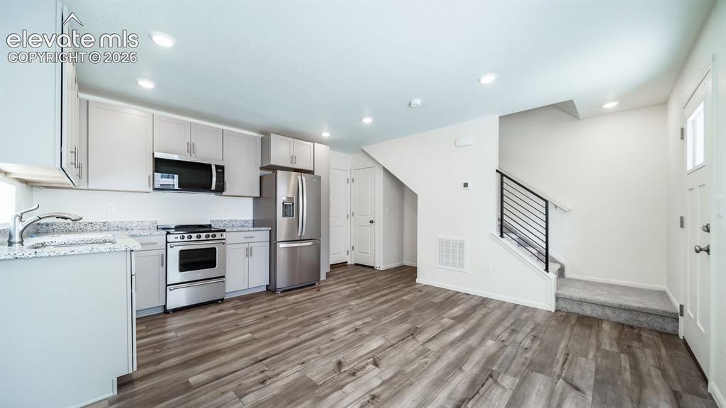 Image 14 of 24: Open-concept living area with wood-finish flooring, recessed lighting, and