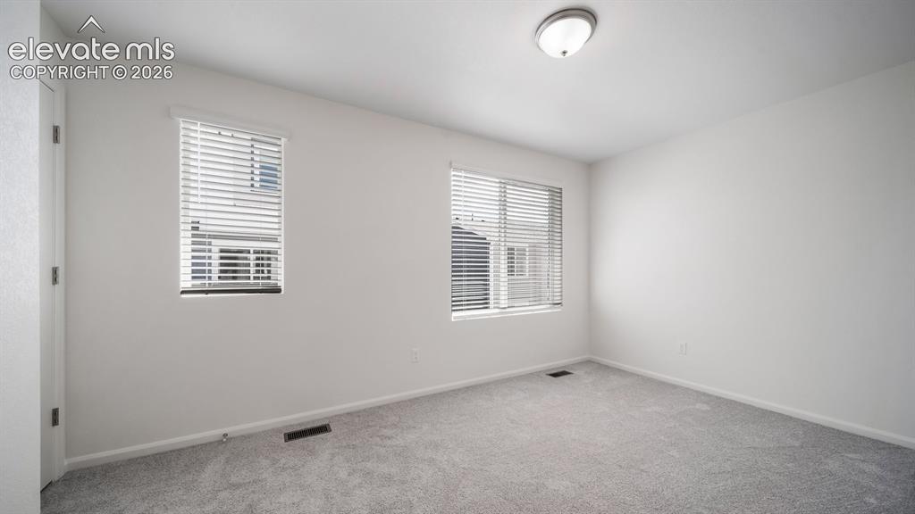 Image 9 of 24: Bright room featuring two windows with white blinds, neutral wall paint, an