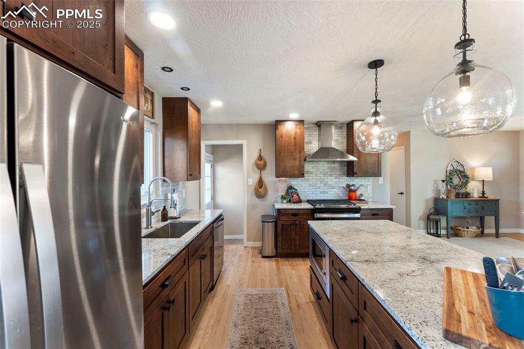 Image 10 of 45: Kitchen with stainless steel appliances, decorative light fixtures, light s