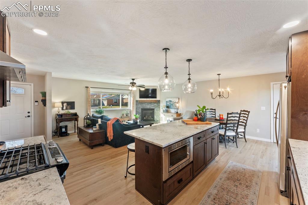 Image 11 of 45: Kitchen featuring light stone counters, a kitchen breakfast bar, a ceiling