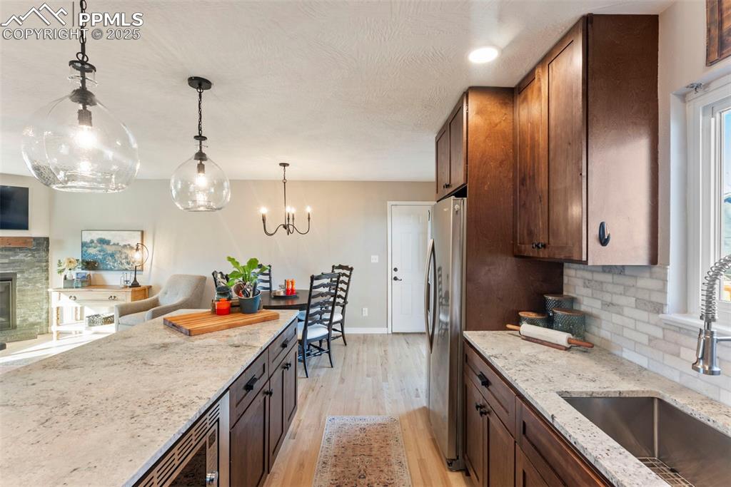 Image 14 of 45: Kitchen featuring light stone countertops, dark brown cabinetry, decorative