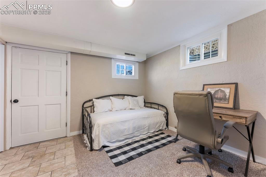 Image 25 of 45: Bedroom with light stone finish floors and a textured wall