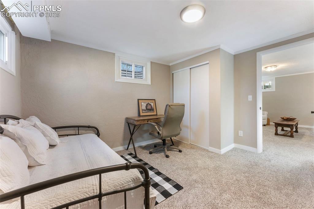Image 26 of 45: Carpeted bedroom with multiple windows, a closet, crown molding, a desk, an