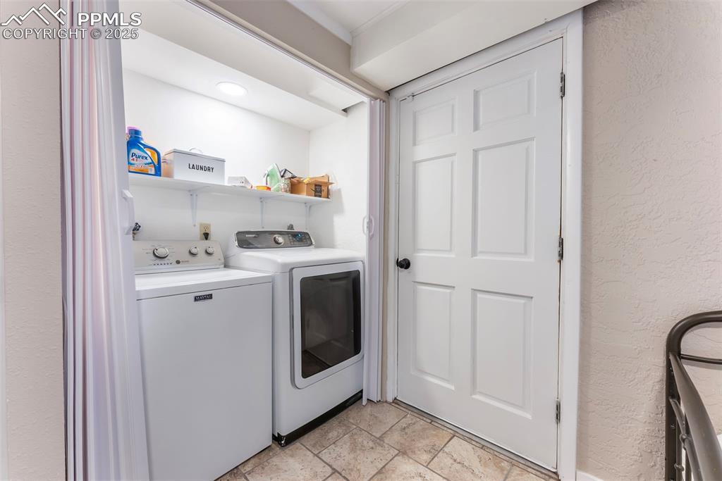 Image 27 of 45: Laundry area featuring a textured wall and washing machine and dryer