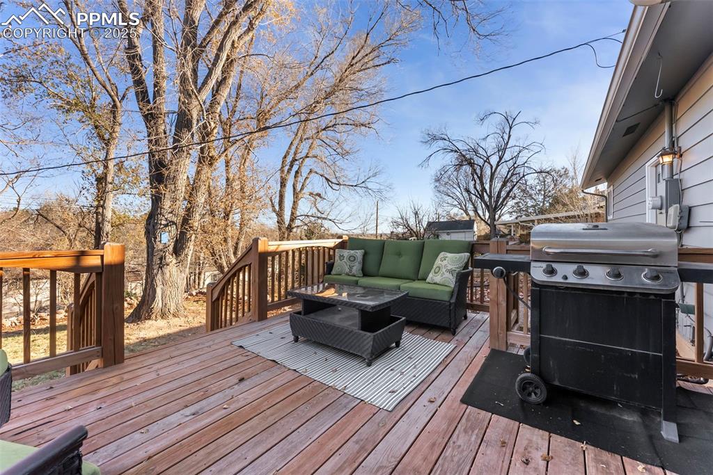 Image 31 of 45: Wooden terrace featuring an outdoor living space and a grill