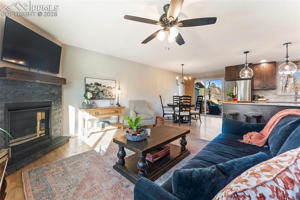 Image 4 of 45: Living room featuring light wood-style floors, a stone fireplace, a ceiling