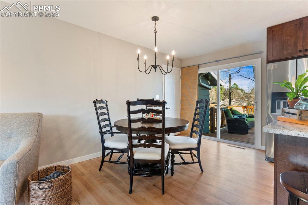 Image 8 of 45: Dining space with light wood-style floors and a chandelier