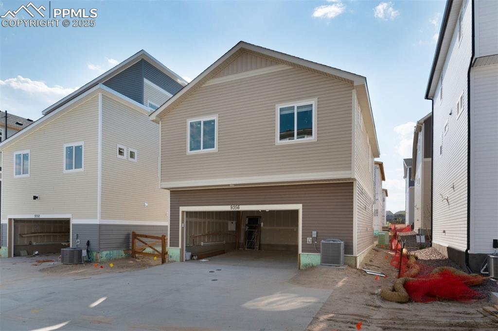 Image 6 of 7: View of side of property featuring a cooling unit and an attached garage