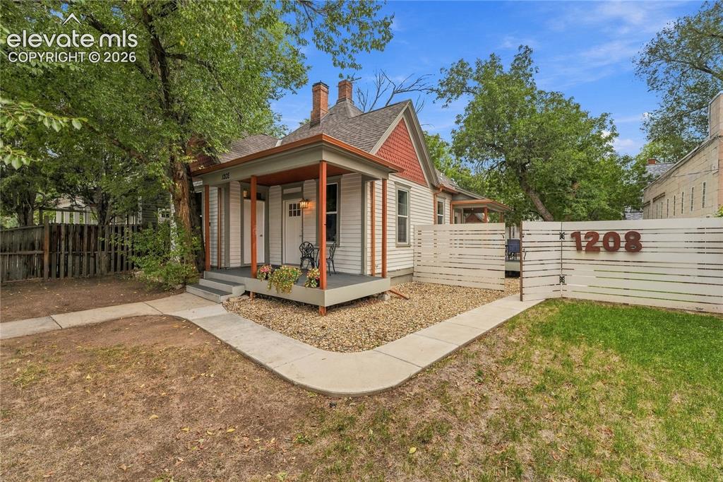 Image 2 of 50: Front of main house with inviting covered front porch and fully fenced fron