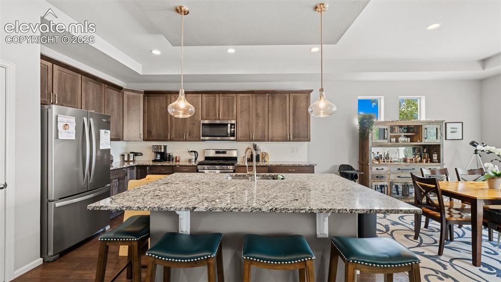 Image 14 of 34: Open-concept kitchen and dining area featuring a large granite-topped islan