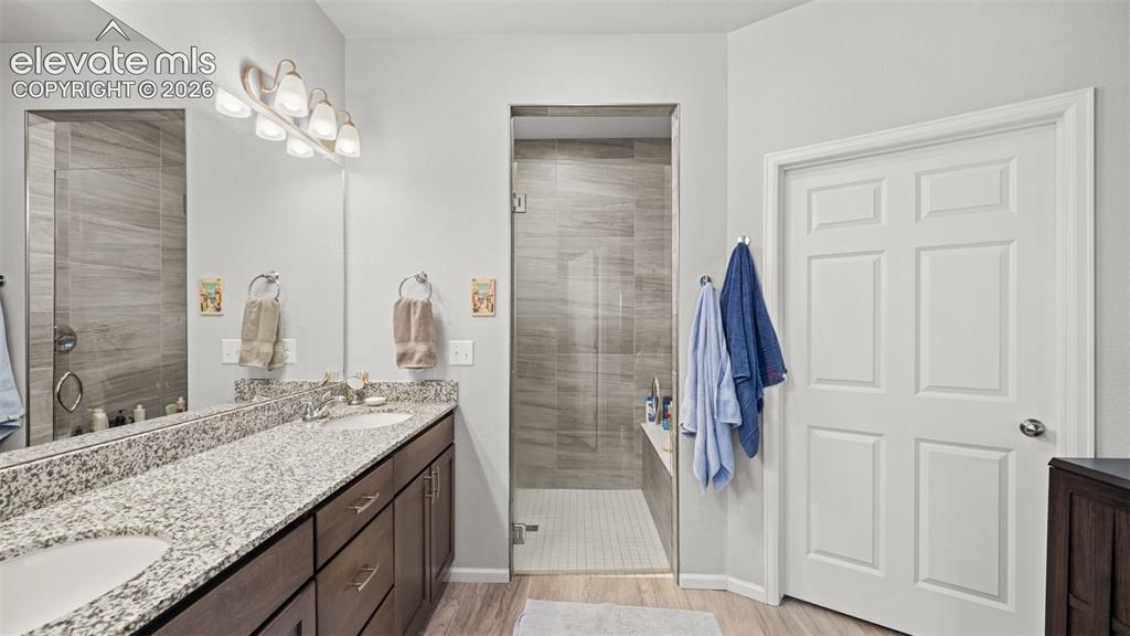 Image 18 of 34: Bathroom featuring a dual-sink vanity with a light granite countertop and d