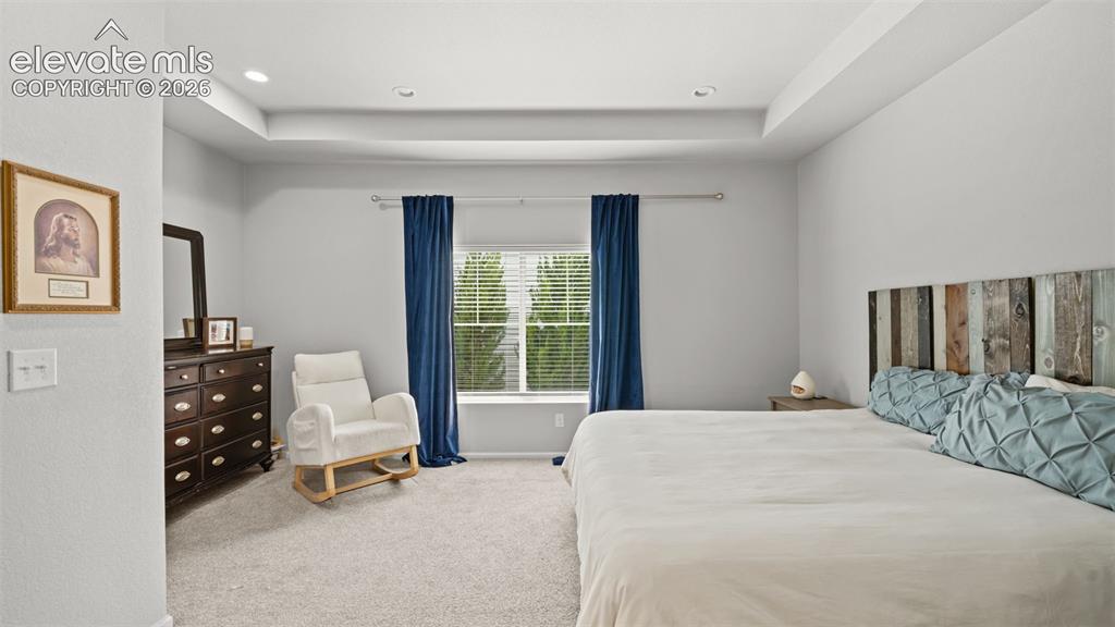 Image 19 of 34: Spacious room featuring tray ceilings with recessed lighting, light-toned c