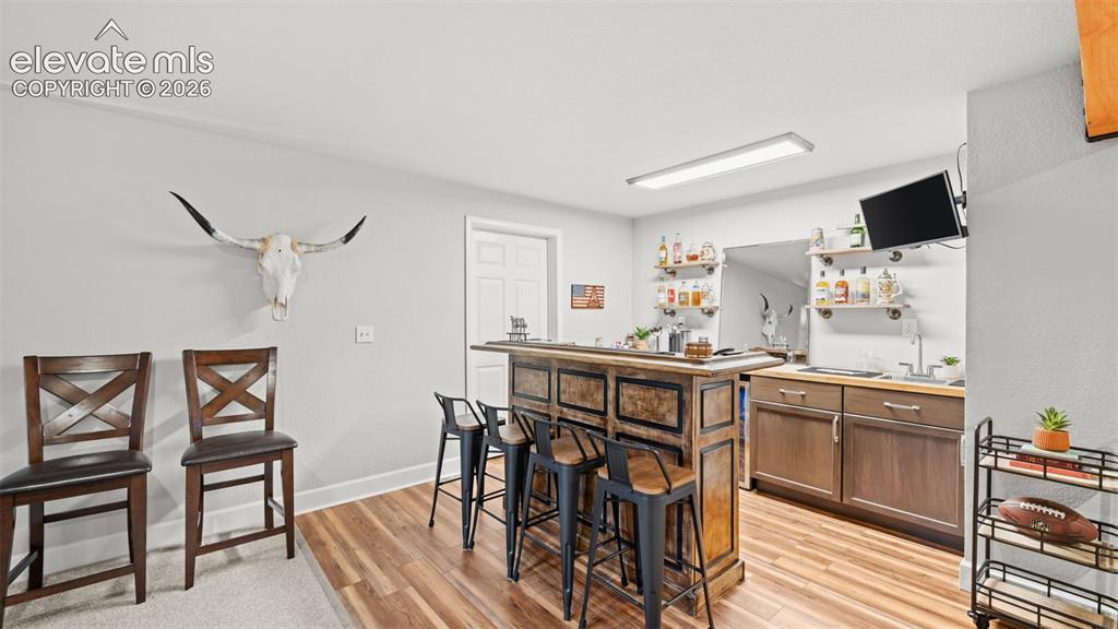 Image 20 of 34: Wet bar featuring wood-finish flooring, built-in cabinetry, a sink, and wal