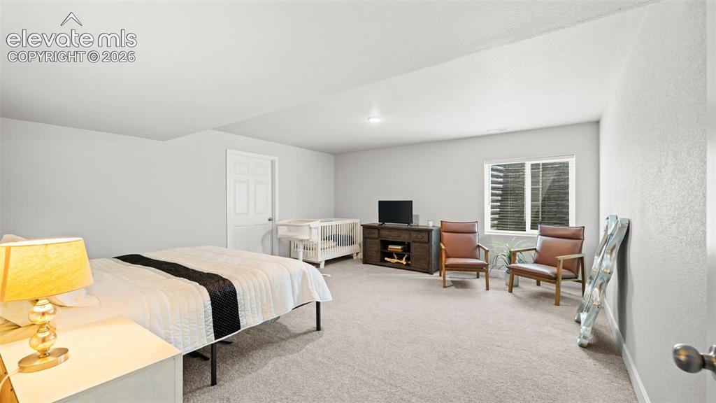 Image 23 of 34: Carpeted room featuring a white paneled door, a window with horizontal blin