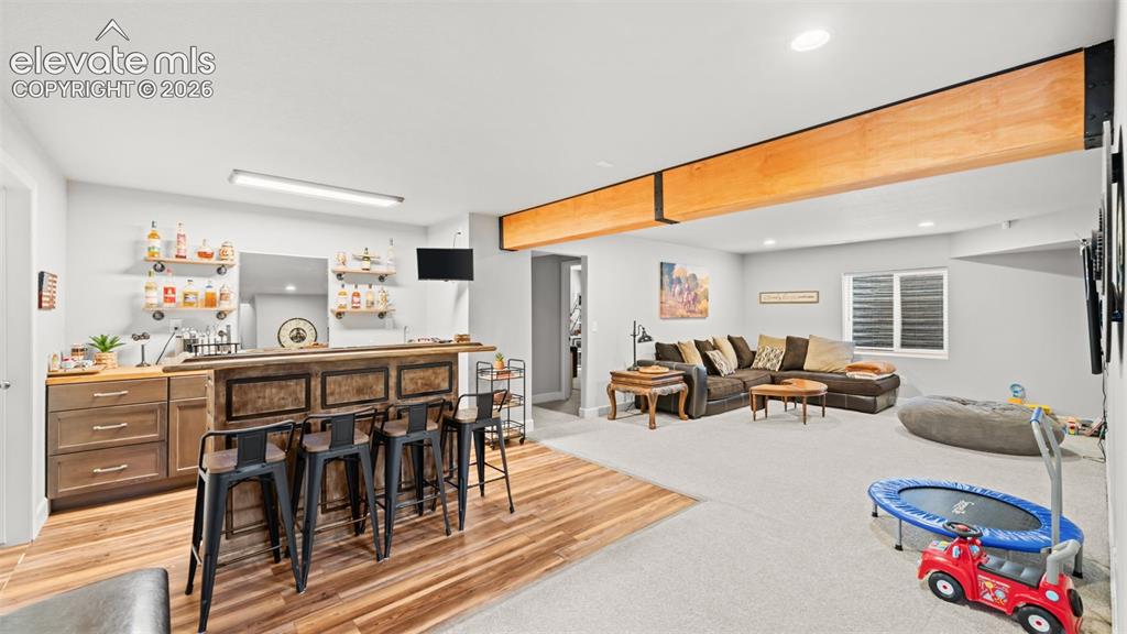 Image 25 of 34: Spacious finished lower level featuring a built-in bar with wood-finish cab